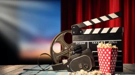 Retro film production accessories placed on wooden planks. Concept of film-making. Red curtain and movie screen on background