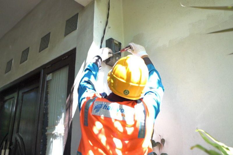 Ilustrasi Petugas PLN saat melakukan penambahan daya pada kWh meter milik pelanggan.