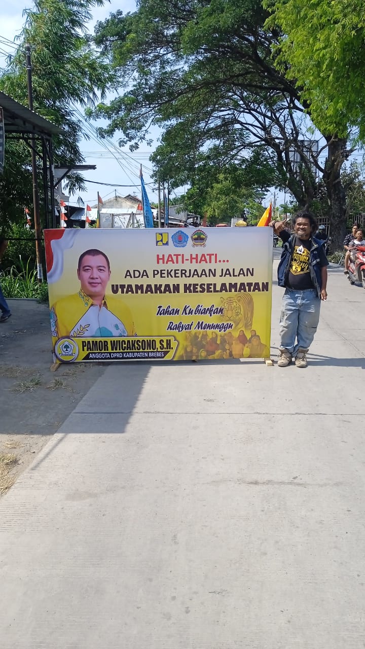 Anggota DPRD Brebes Pamor Wicaksono memasang banner himbauan di ruas jalan Brebes-Jatibarang yang dalam tahap pengerjaan pada Kamis (27/11). Foto: Istimewa